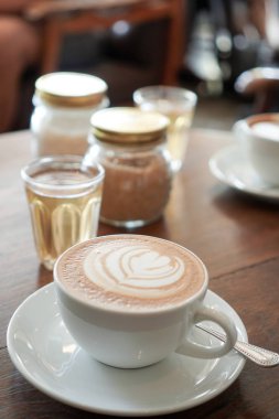 Yaprak desenli ahşap backg üzerinde beyaz bir fincan kahve