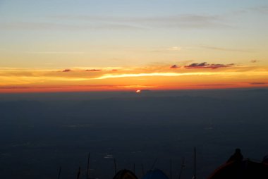 Kışın dağda gün doğumu ön planda bir çadırla.