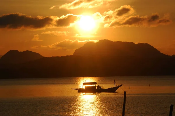 Gün batımında dağın önünde bir balıkçı teknesi. 