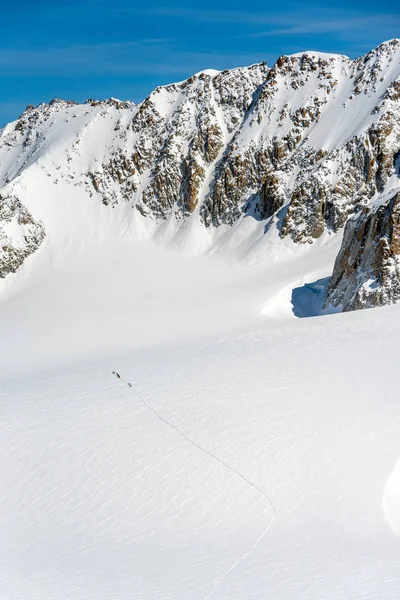 登山家は巨大な雪に覆われた氷河を横断する山の中で一つのファイルを歩いて高い — ストック写真