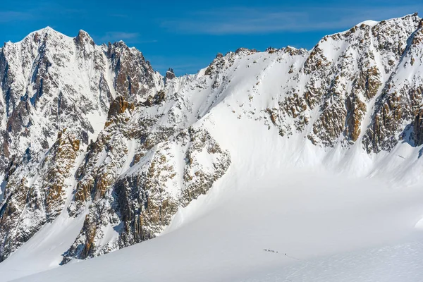 登山家は巨大な雪に覆われた氷河を横断する山の中で一つのファイルを歩いて高い — ストック写真