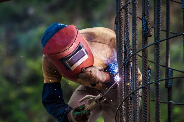 Construction worker welding rebars for reinforced concrete pillars
