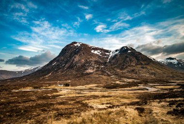 İskoçya Highland 'da karla kaplı bir dağın altında ıssız bir ev, A82 yolunun hemen dışında.