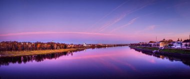 Güneş, Rusya 'nın Tver şehrindeki Volga nehrinin üzerinde batıyor. Gökyüzünü ve aynaya benzeyen yansımasını çeviriyor. Koyu mavi ve mor.
