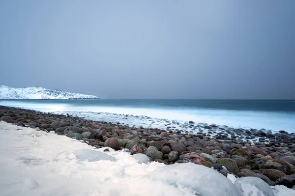 Longa Exposição Surfe Quebrando Pedras Pedra Uma Praia Coberta Neve — Fotografia de Stock