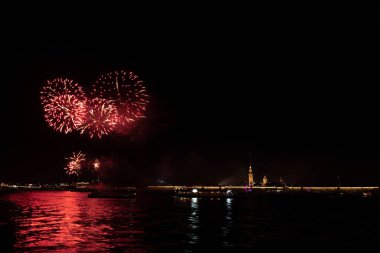 Saint Petersburg, Rusya 'daki Neva nehrinin üzerinde kırmızı havai fişekler. Sağda eski Peter ve Paul kalesinin duvarları ve katedrali var.