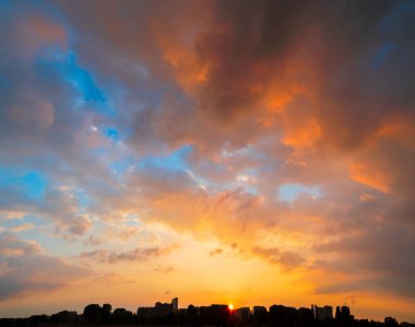 Şehir manzarası silueti gün batımında görkemli bir gökyüzünün altında binaların arkasında güneş batıyor ve bir sürü kopya alanı var.