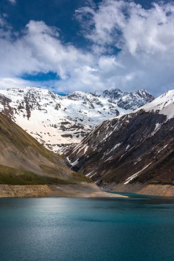 Dağlarda kar ve buzullar erir ve bir su deposunu doldurur (bu durumda Isre bölgesindeki Fransız Alplerindeki Lac de Grand Maison)