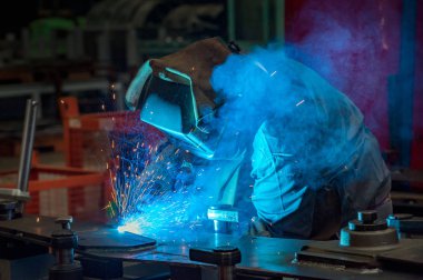 Welder at work in a factory in full protective gear - Personal protective equipment (PPE)