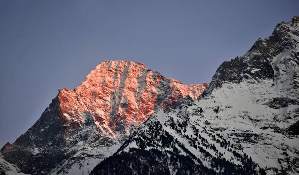 Sunset on the mountains: the snow capped peak turns red as it catches the last light of the day. Italian Alps in the Aosta Valley.