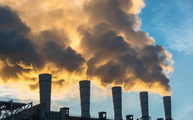 Endüstriyel bacalar mavi gökyüzüne duman ve is saçarak havayı kirletiyor ve sera gazları ve CO2 emisyonlarıyla küresel ısınma ve iklim değişikliğine neden oluyor.