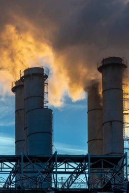 Endüstriyel bacalar mavi gökyüzüne duman ve is saçarak havayı kirletiyor ve sera gazları ve CO2 emisyonlarıyla küresel ısınma ve iklim değişikliğine neden oluyor.