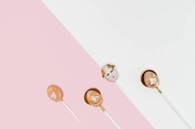 Paskalya sınır kompozisyonu, altın madalyalı yumurtalar, pembe arka planda kaşıklar. Şık dekorasyon, asgari paskalya konsepti. Uzayı kopyala Şenlikli düz zemin arkaplan tebrik kartı. 