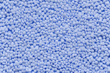 Pile of blue plastic resin granules. Granular texture background. Classic blue color of the year 2020 clipart