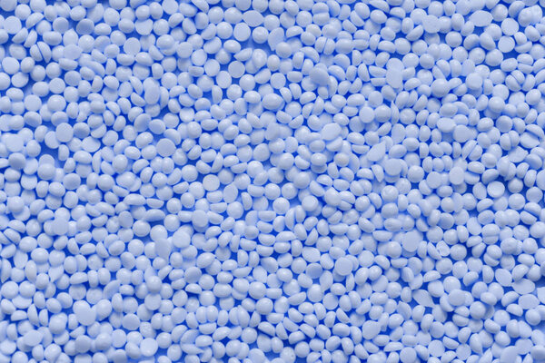 Куча синих пластиковых гранул смолы. Гранулярный текстурный фон. Классический синий цвет 2020 года

