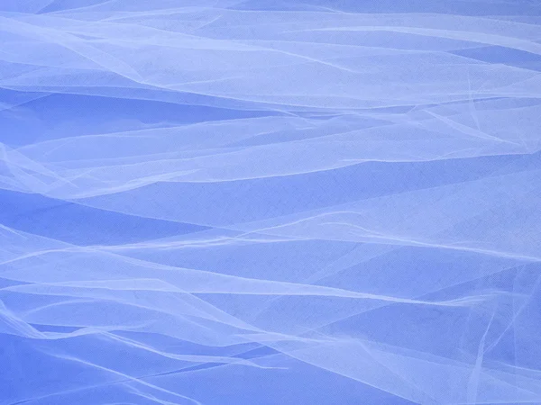 Lightweight fabric mesh lace on blue paper, texture of the fabric is beautifully draped background. Abstract soft chiffon veil backdrop. Bride concept. Classic blue color of the year 2020