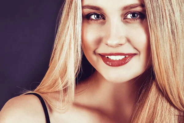 Schöne junge blonde Frau mit langen glatten Haaren auf dunklem Hintergrund — Stockfoto