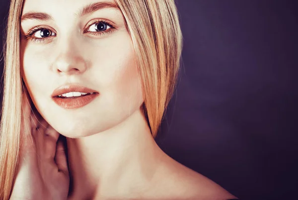 Schöne junge blonde Frau mit langen glatten Haaren auf dunklem Hintergrund — Stockfoto