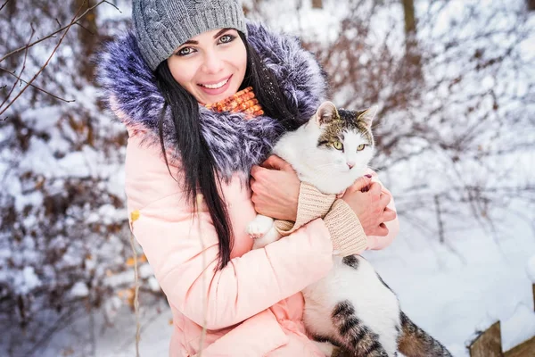 Winter. A girl holding a cat in snow — Stock Photo, Image