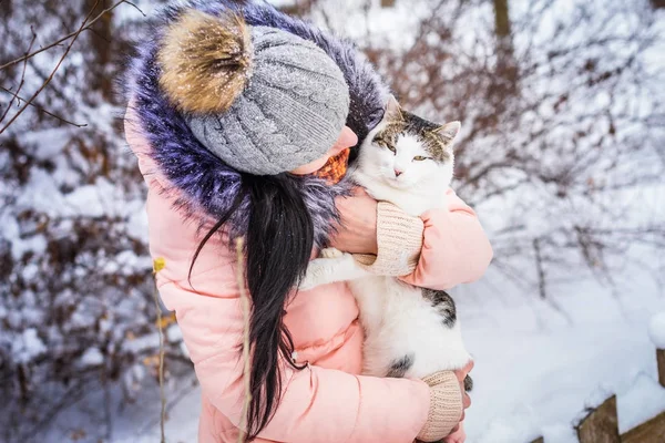 Inverno. Uma menina segurando um gato na neve — Fotografia de Stock