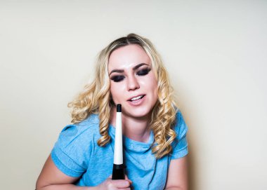 Bir kadın bir saç aksesuarı şarkı için bir mikrofon olarak kullanır