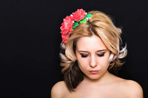 Woman with blonde laying and rimmed with red flowers on a dark background — Stock Photo, Image