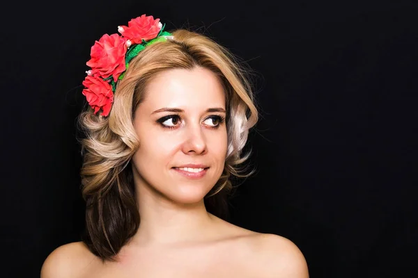 Woman with blonde laying and rimmed with red flowers on a dark background — Stock Photo, Image