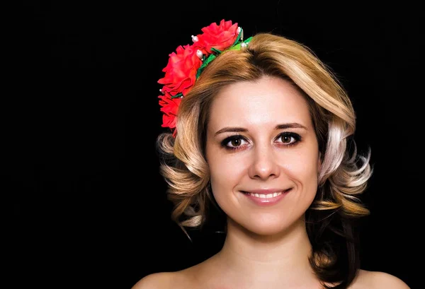 Woman with blonde laying and rimmed with red flowers on a dark background — Stock Photo, Image