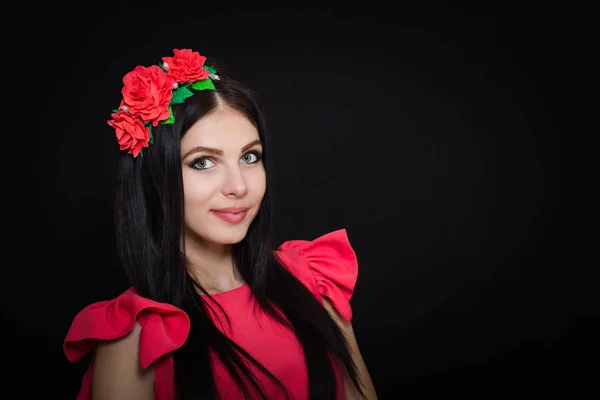 Donna con lunghi capelli neri e ghirlanda con fiori rossi su sfondo scuro — Foto Stock