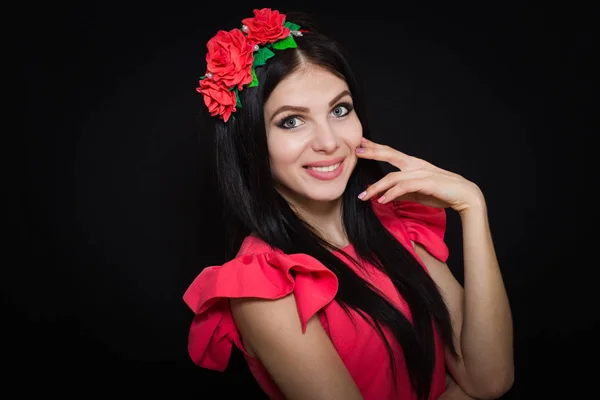 Жінка з довгим чорним волоссям і вінком з червоними квітами на темному тлі — стокове фото