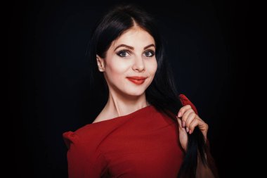 Karanlık bir arka plan üzerinde mavi gözlü güzel esmer kadın saçı tutar