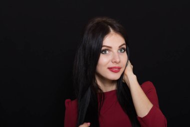 Karanlık bir arka plan üzerinde mavi gözlü güzel esmer kadın saçı tutar