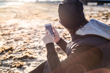 Adam oturuyor ve bir telefon tutarak 