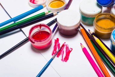 Guaj boya fırçaları ve hafif bir arka plan üzerinde renkli kalemler