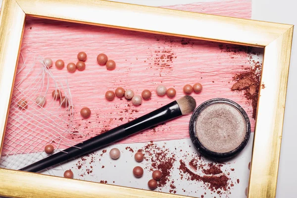 Cosmetics. Scattered shadows, applicator, balls of blush  in a gold frame. Abstraction — Stock Photo, Image