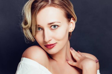 Karanlık bir arka plan üzerinde kısa bir şık saç kesimi ile sarışın kız