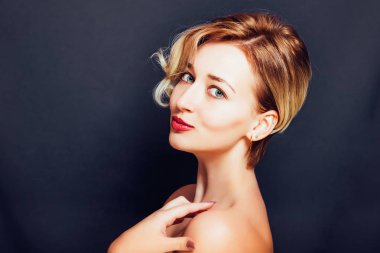 Karanlık bir arka plan üzerinde kısa bir şık saç kesimi ile sarışın kız