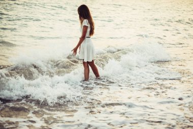 Bir kadın deniz kenarında yürüyor