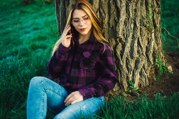 Blondes Mädchen in der Nähe eines Baumes telefoniert — Stockfoto