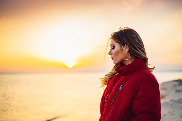 Blondes Mädchen auf dem Hintergrund des Meeres und Sonnenuntergangs Stockbild