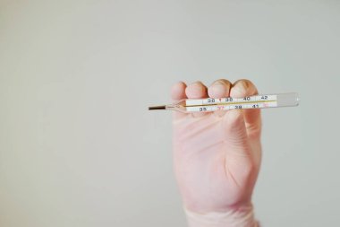 Tıbbi eldivenlerin içinde termometre var. Yakın plan.