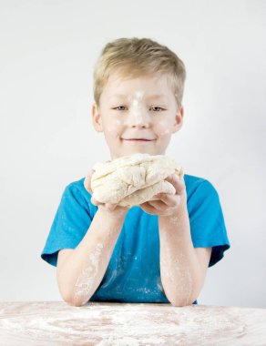 Küçük çocuk elinde bir hamur tutuyor. Aşçı