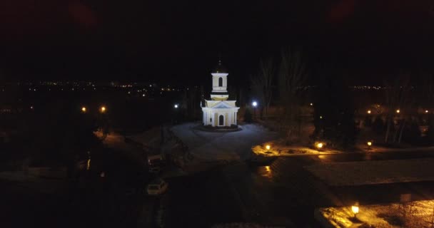 Aerial view white church with golden domes stands at night in a dark park — Stock Video