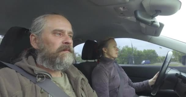 Sidovy av fönster, Senior man rider i bilen med en kvinna vid ratten — Stockvideo