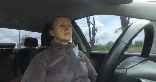 成熟的妇女司机坐在汽车车轮上, 聚精会神地看着路 — 图库视频影像