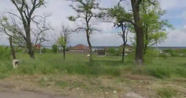 Vista desde la ventana del coche en el borde de la carretera de campo con campos y casas — Vídeo de stock