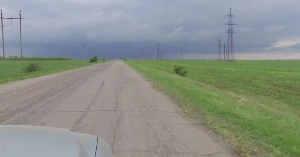 Kijk vooruit vanuit raam van de rijdende auto aan agrarische velden met elektrische paal — Stockvideo