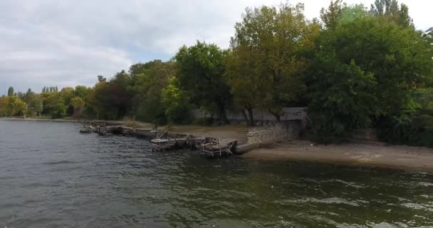 Vista aérea Operador de dron en la orilla del río entre árboles verdes cerca de una bicicleta — Vídeos de Stock