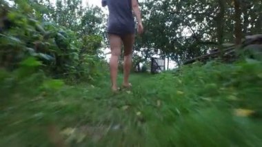 Kadın ayakları, sabah Bahçe ile güneş arasında yeşil çim boyunca yürüyüş görünümünü