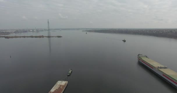 Luchtfoto rivier sleepboot trekt roestig bak in de buurt van droge lading tanker langs rustige rivier — Stockvideo